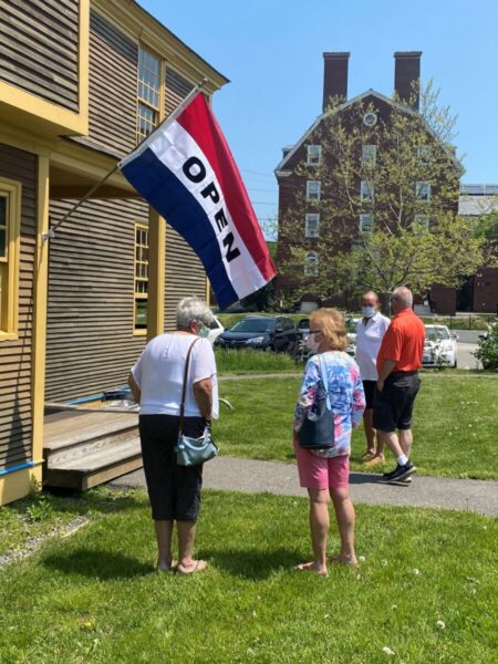 Outdoor shot of the entrance to Folsom Tavern with an OPEN sign showing and four people on a tour.
