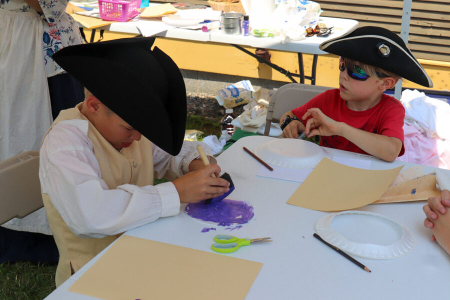 Children wearing tricorn hats making their own stamps on paper plates