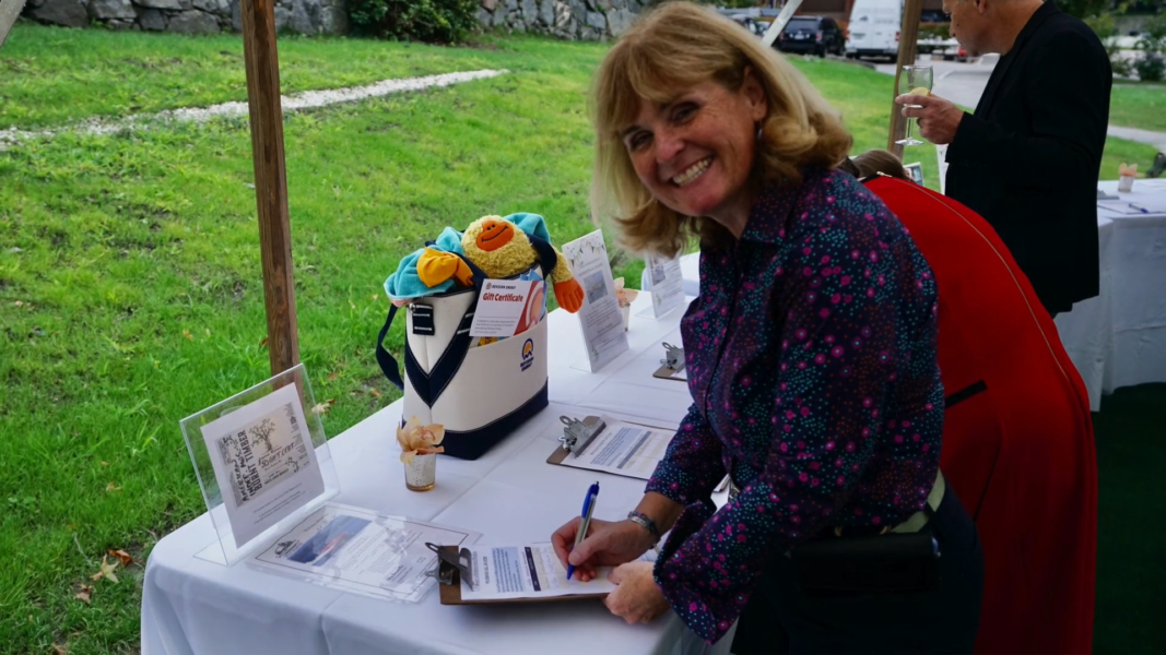 Woman places a bid in the silent auction during the museum's 300th Anniversary event
